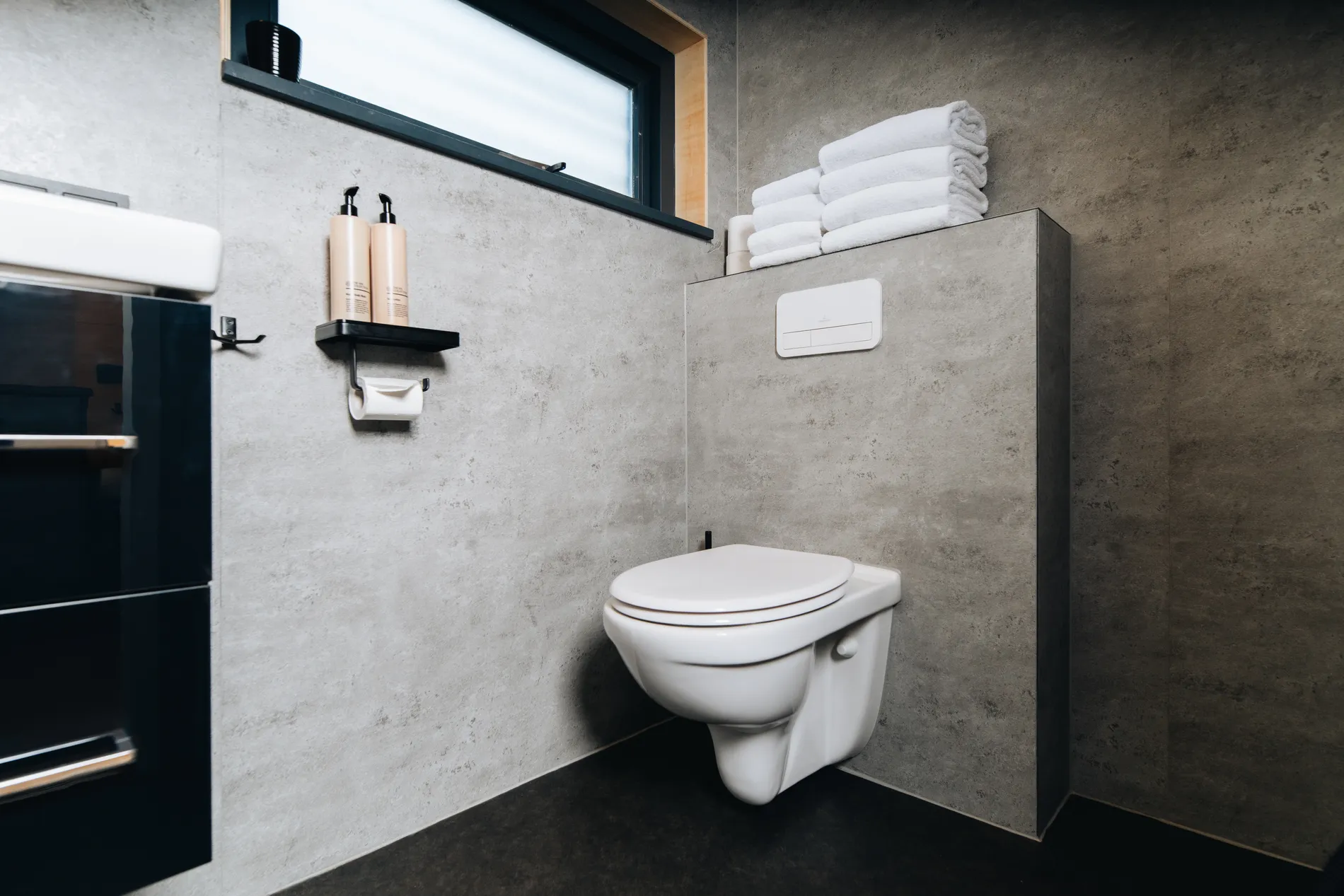 Modern wandcloset in een lodge-badkamer met grijze betonlook tegels.